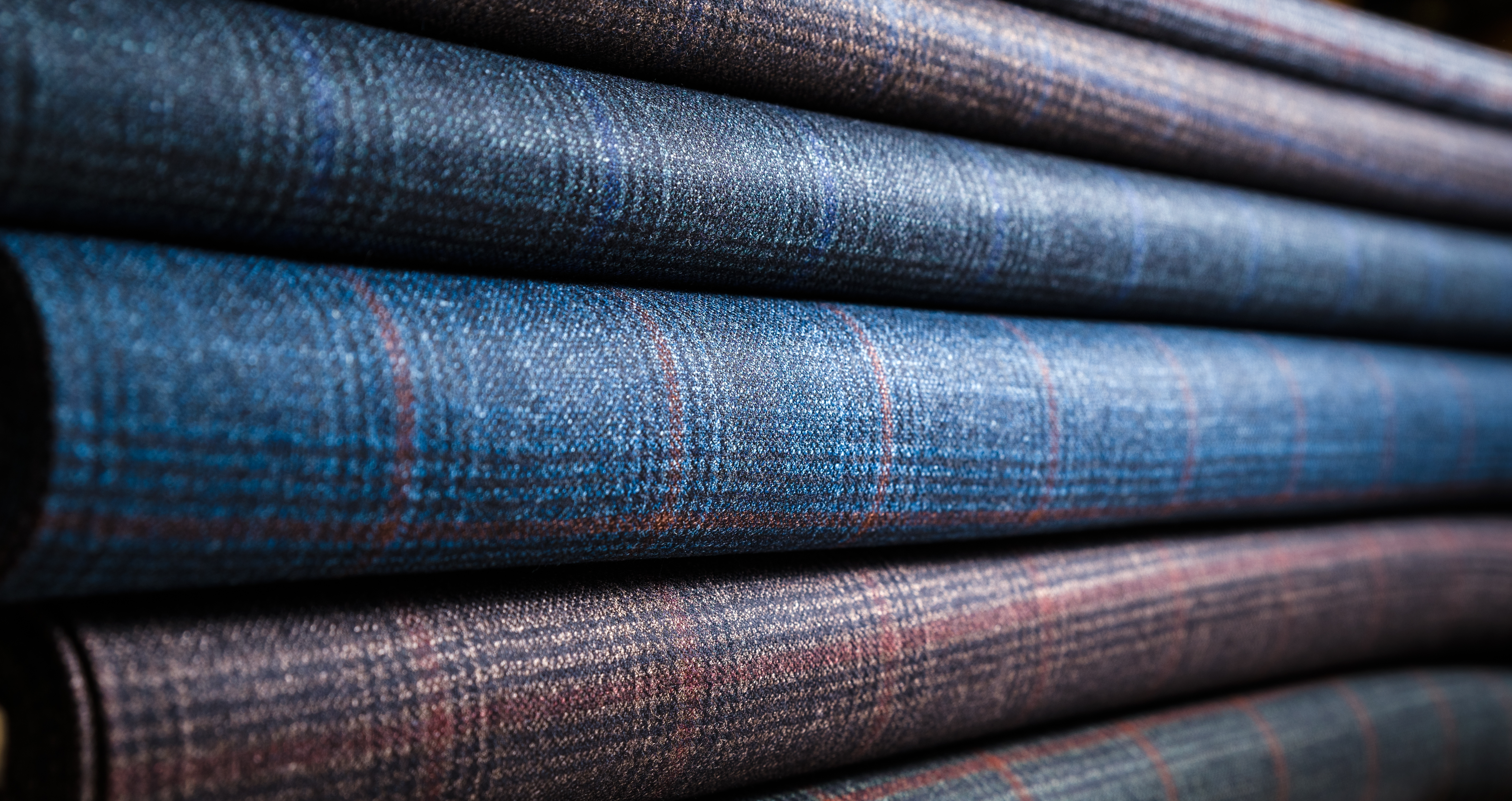 Rolls of curated blue and earth-toned suiting wool fabrics