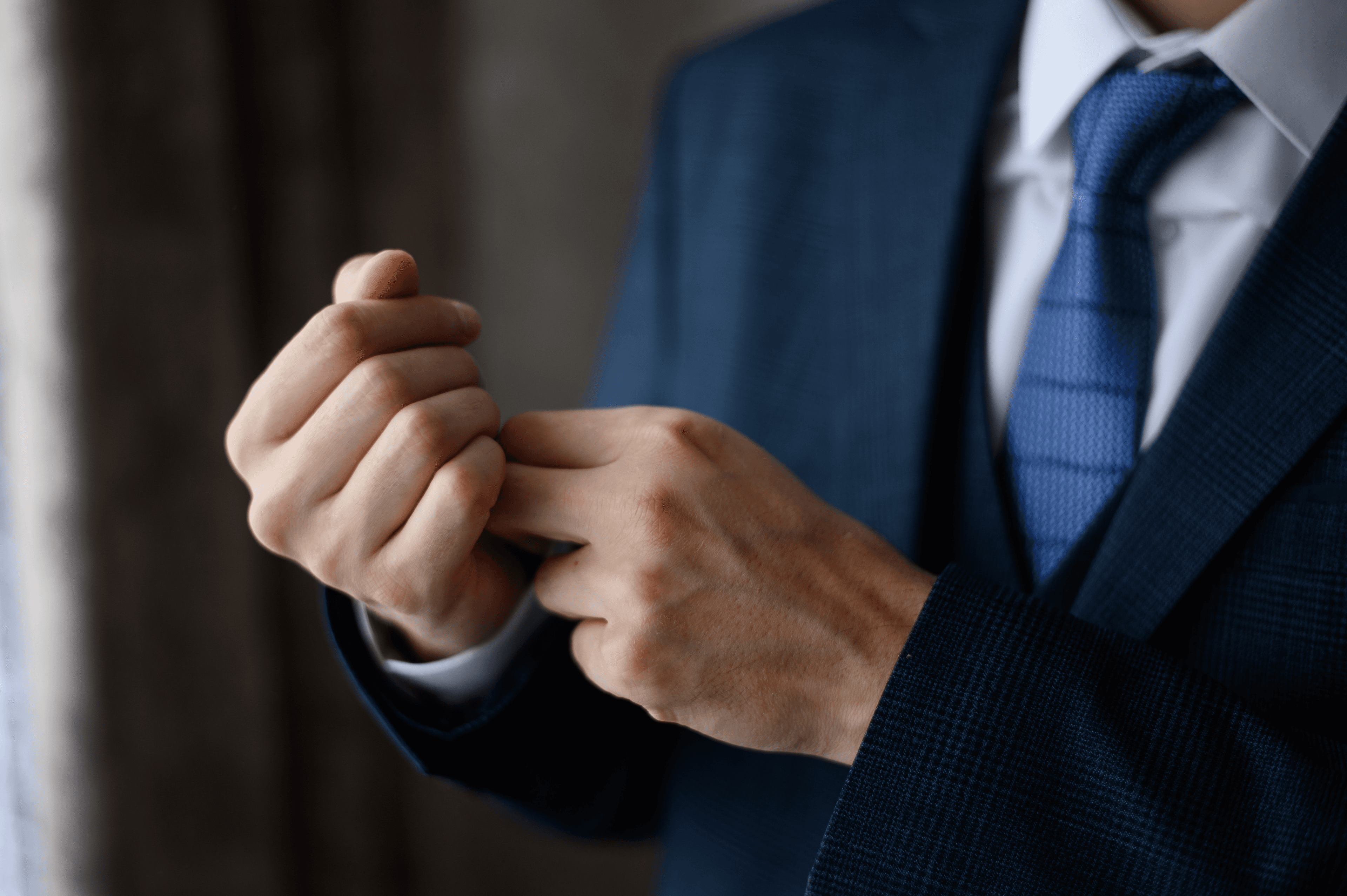A gentleman adjusting the hand-stitched cuff of a bespoke suit